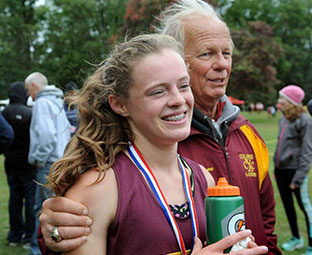 high school female runner hugs her coach