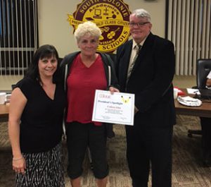 two board members present bus driver with an award