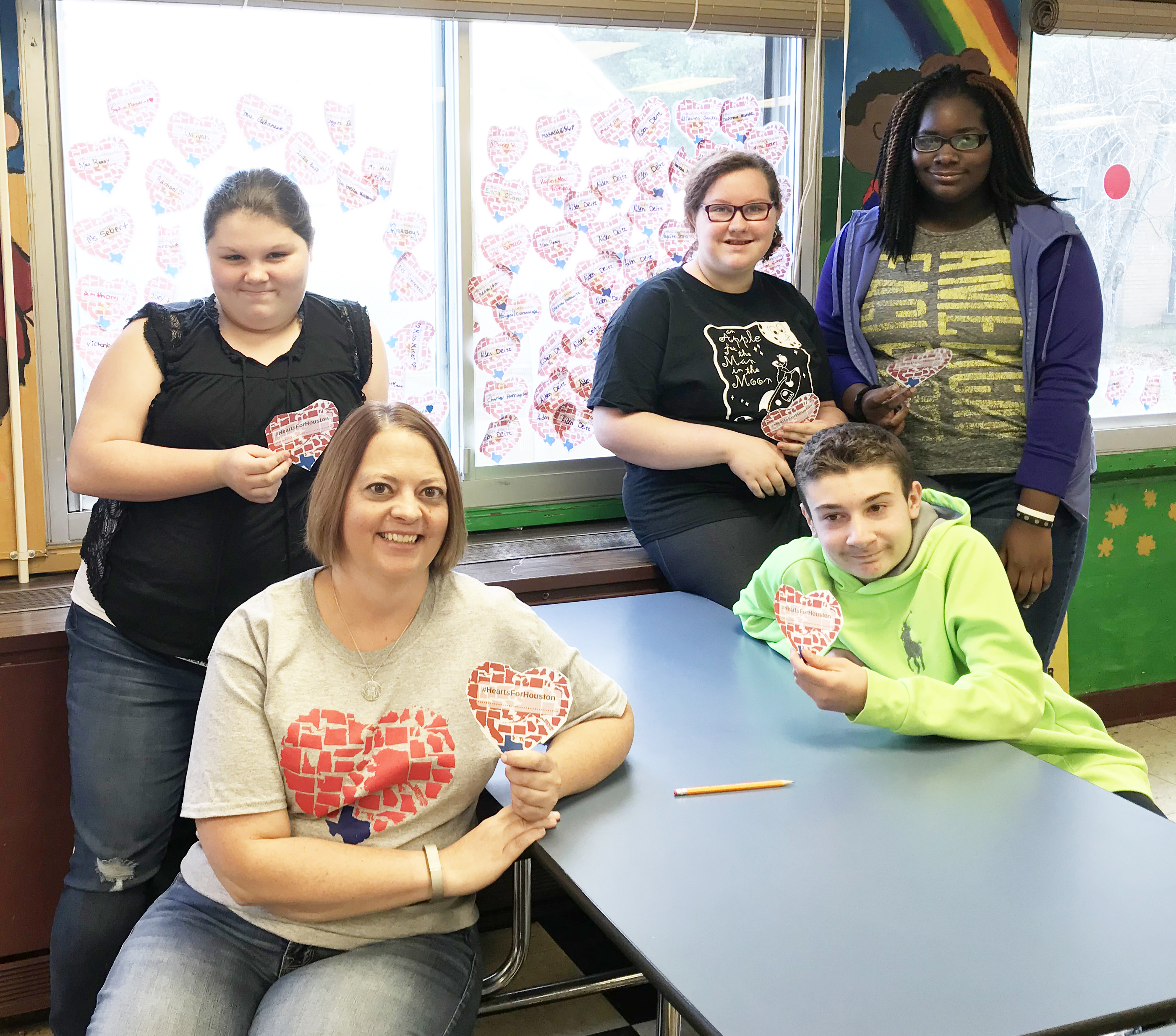 four students and their teacher hold up paper hearts