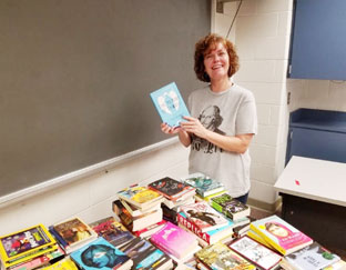 teacher sorts stacks of books on a table