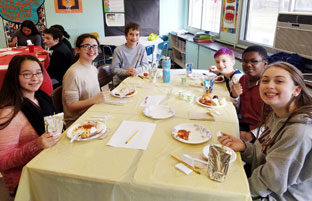 students gather at a table to eat lunch