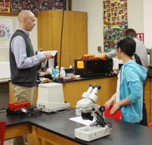 science teacher works with high school students