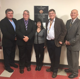 board of education members stand in front of new library plaque