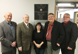 Board of ed members pose in front of new wall plaque