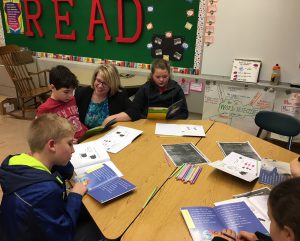 Elementary principal reads at a table with a group of children