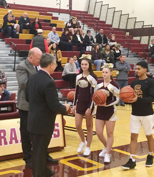 basketball player and cheerleaders present Steck with 2 basketballs