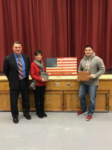 three people displaying an American flag