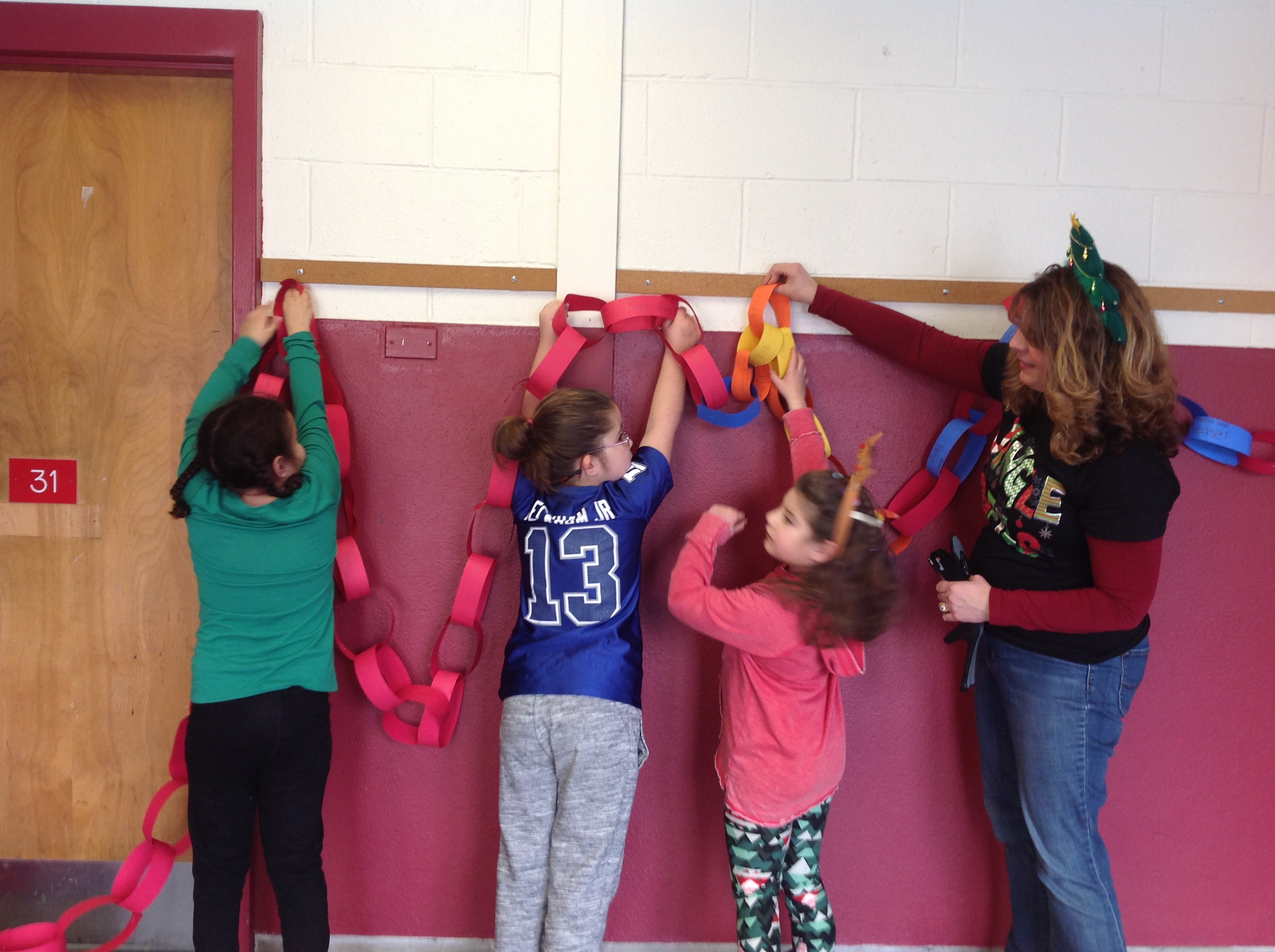 student hang kindness chain in school hallway with teacher