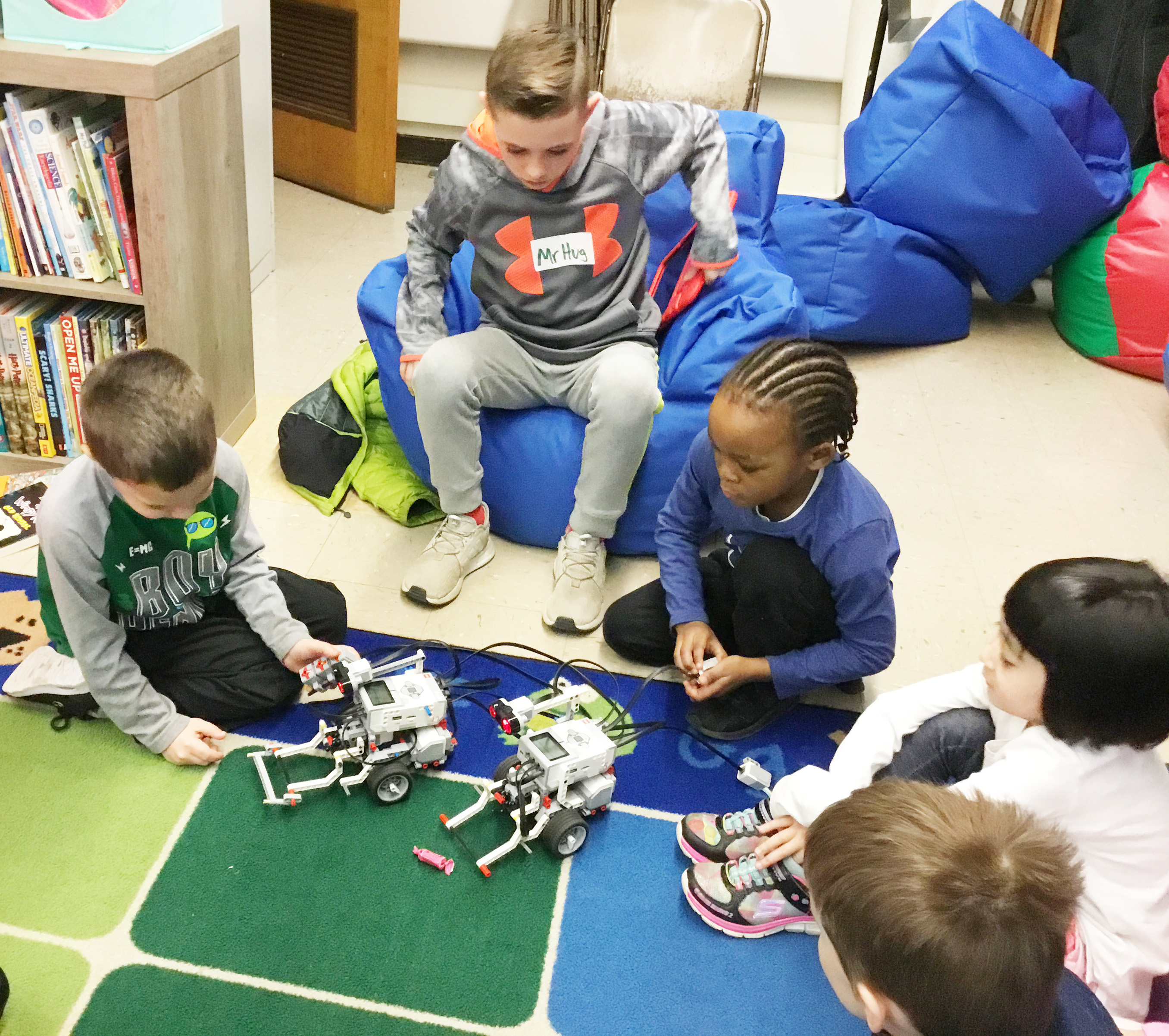 students work with robots on the classroom floor in a large group