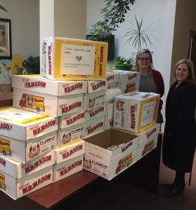 two women stand in front of a pile of boxes