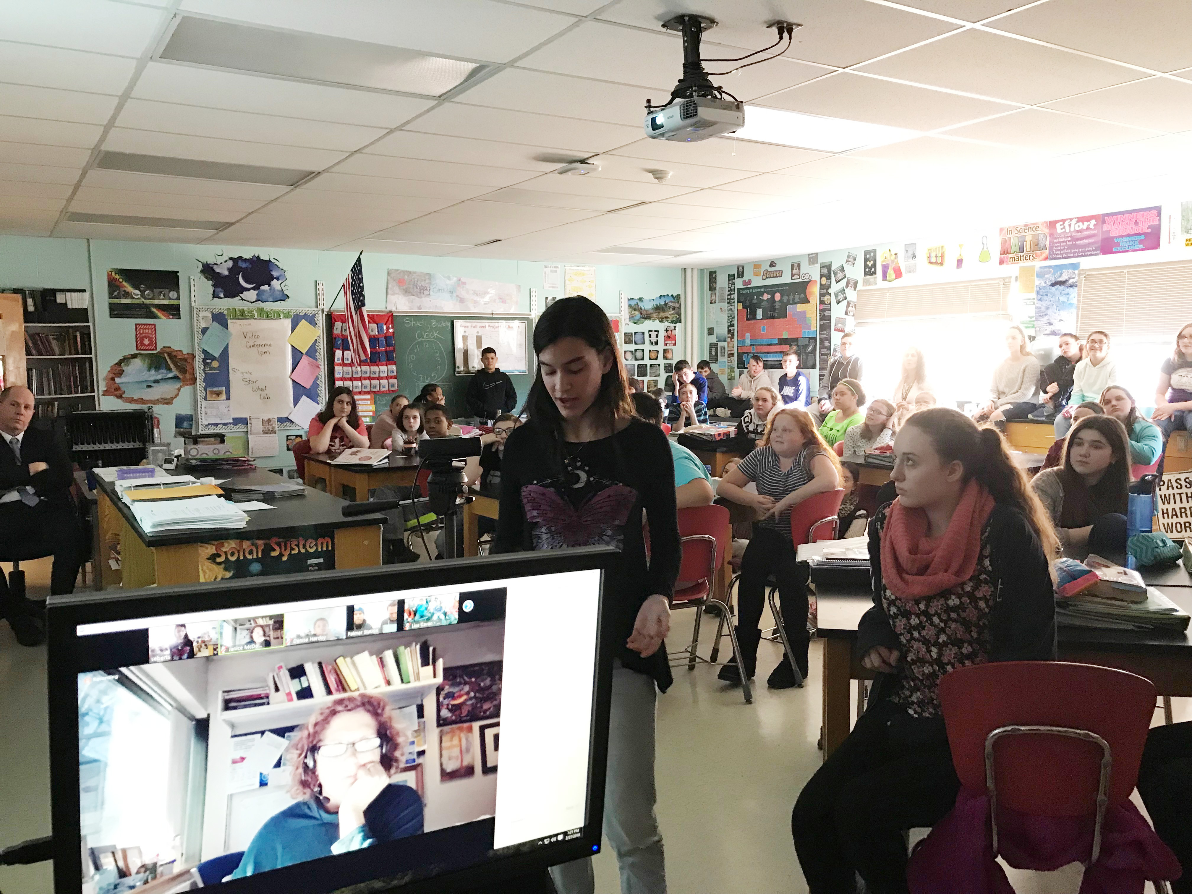 students gather in classroom to view video conference