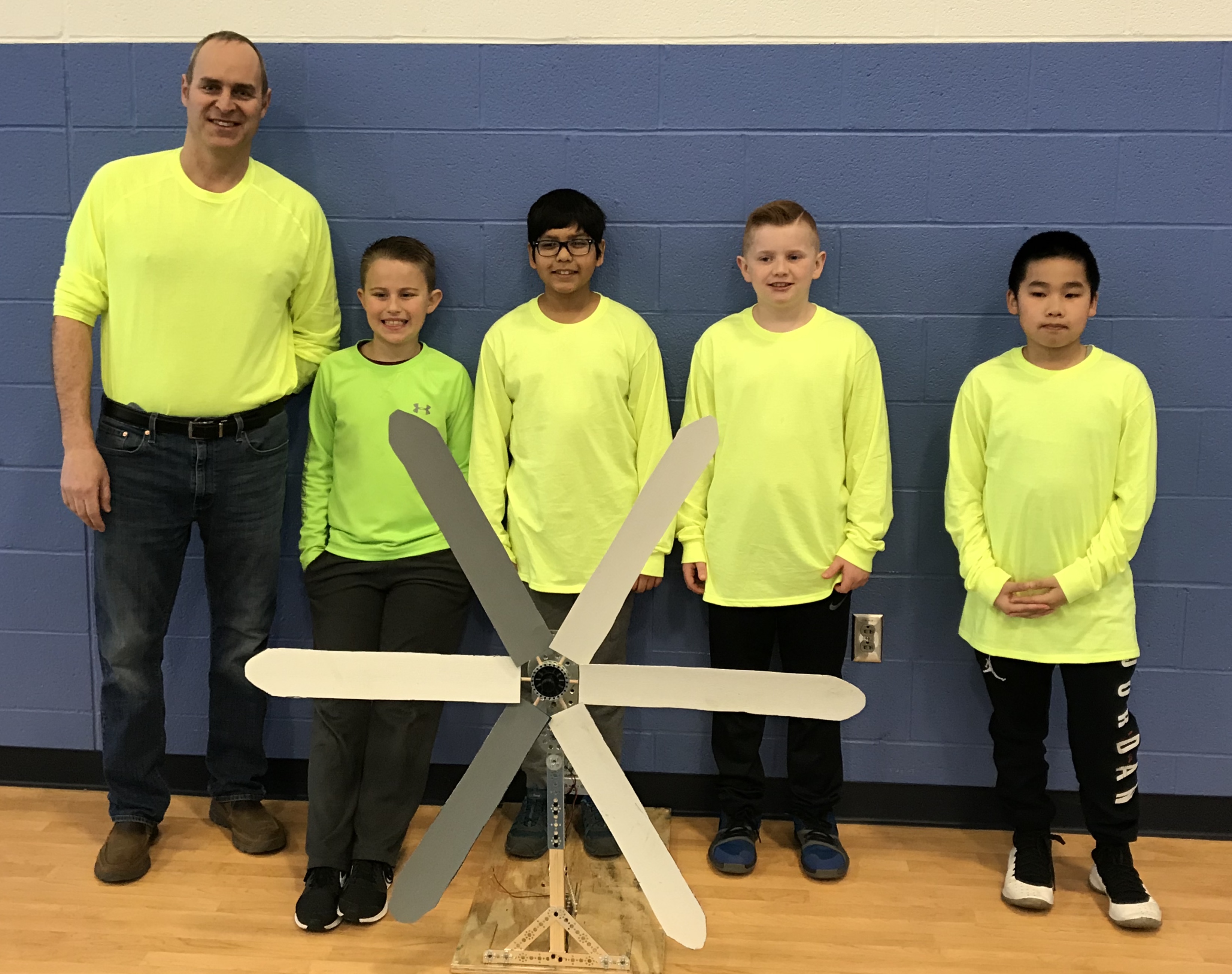 four students and their teacher stand with their STEM design project