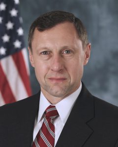 portrait of a man in a suit in front of an American flag