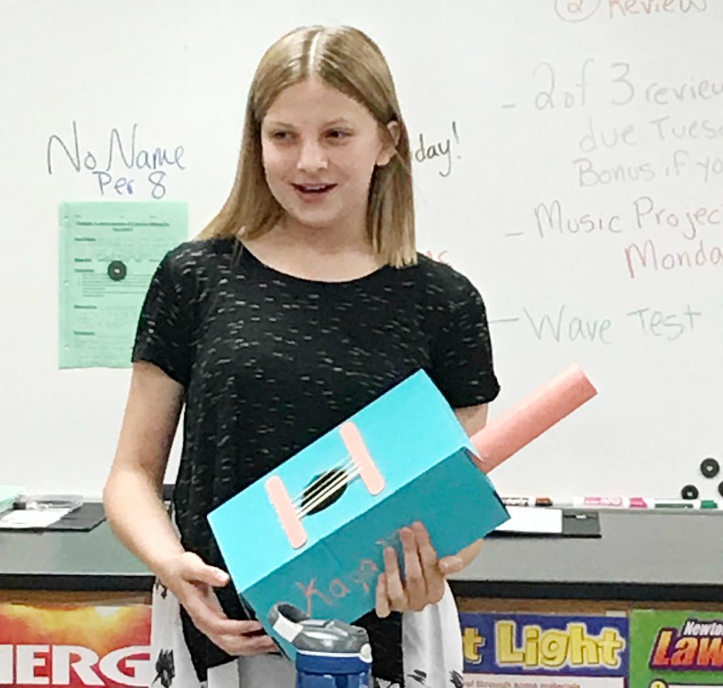 girl displays a homemade guitar