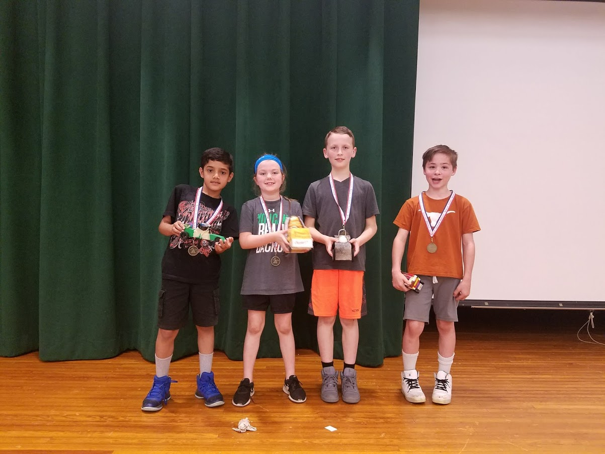 four students stand with their winning trophies