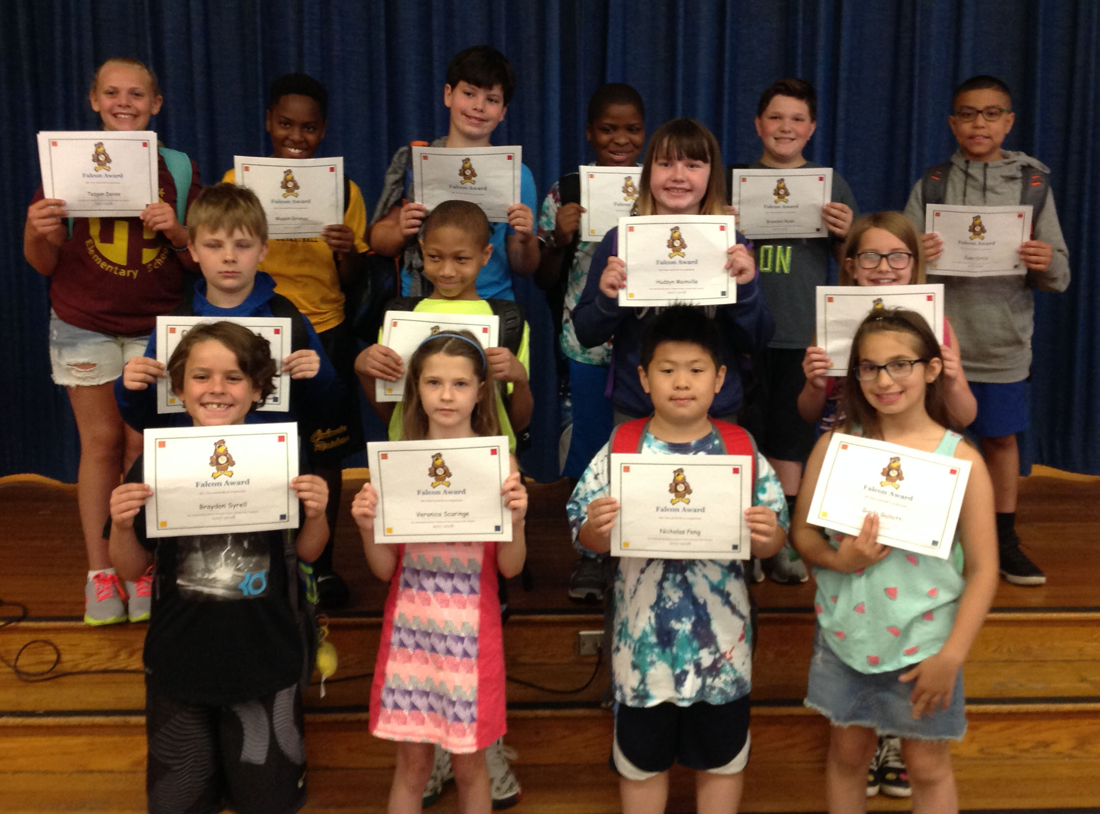 students hold their award certificates on stage