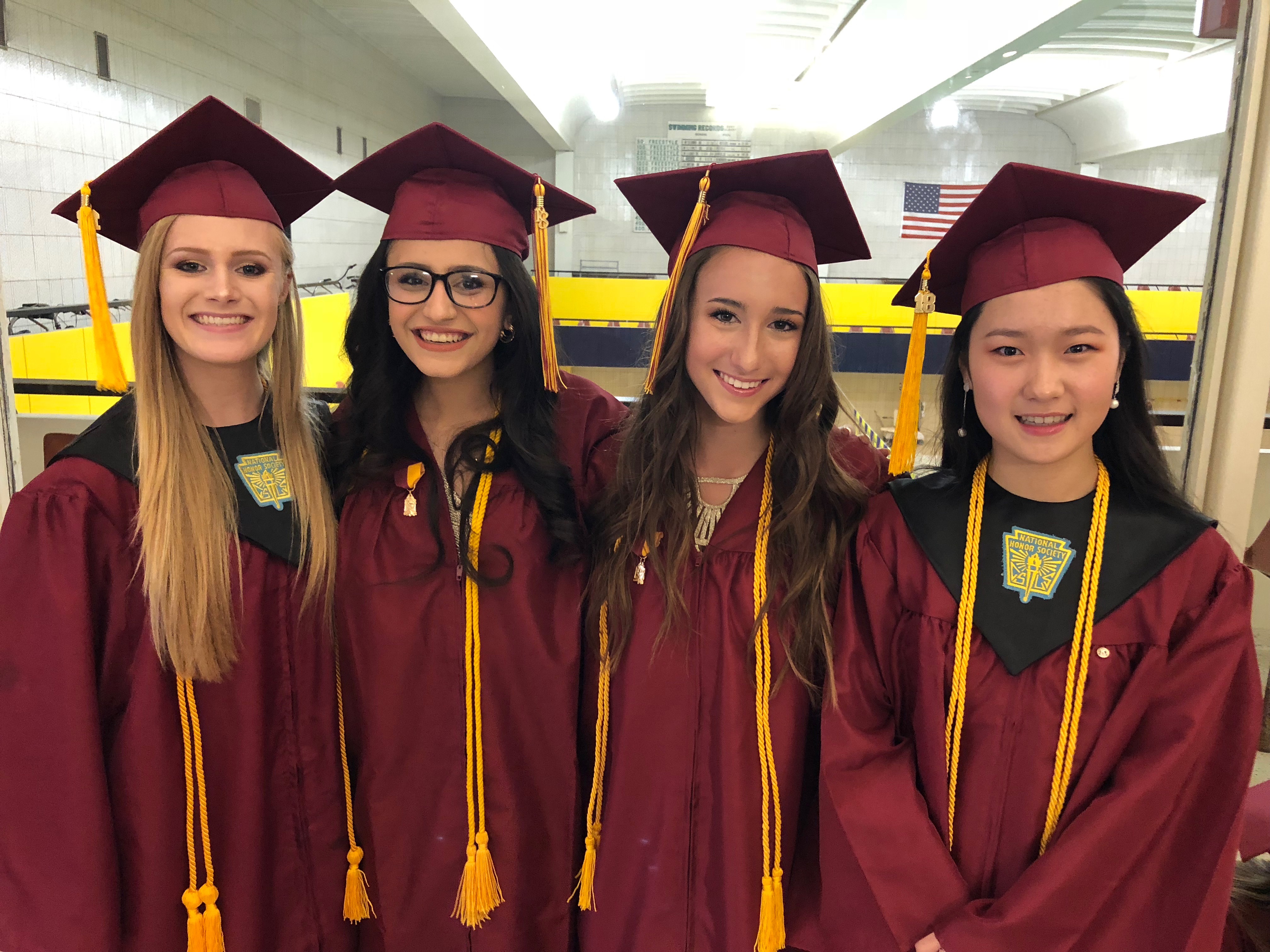 4 female graduates pose in their caps and gowns