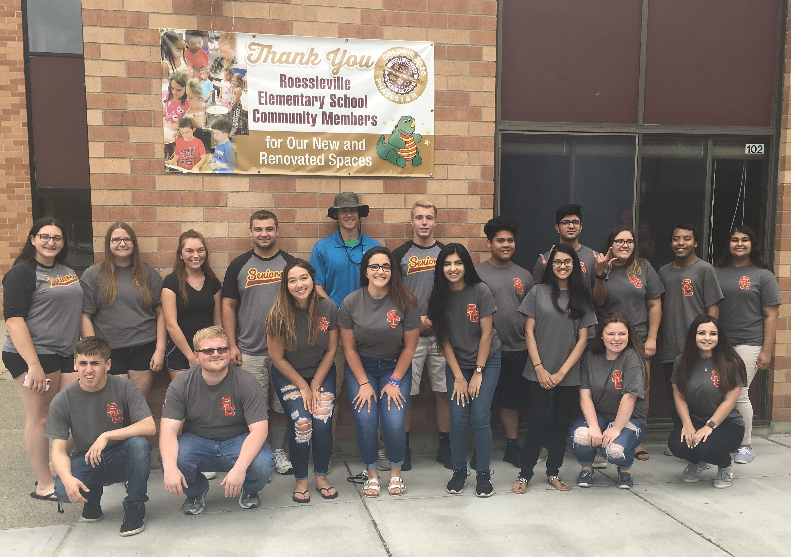 Group of high school senior pose outside elementary school building