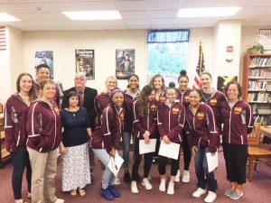 the girls basketball team poses with the school board