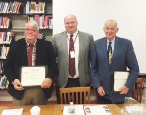 three men stand with awards