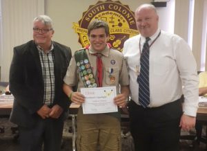 2 men present an award to a Boy Scout