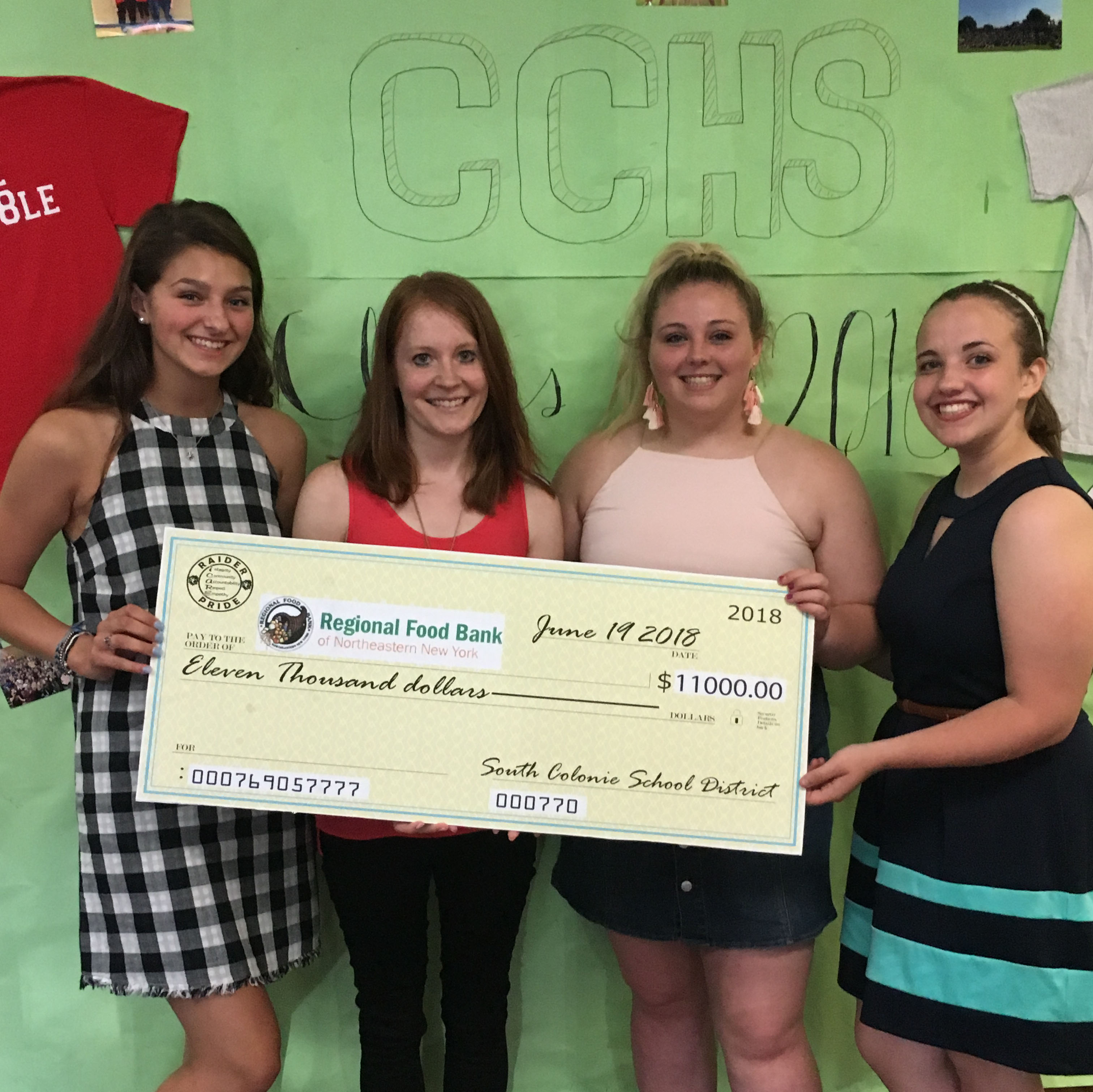 three students present large check for 11,000 dollars to Regional Food Bank woman