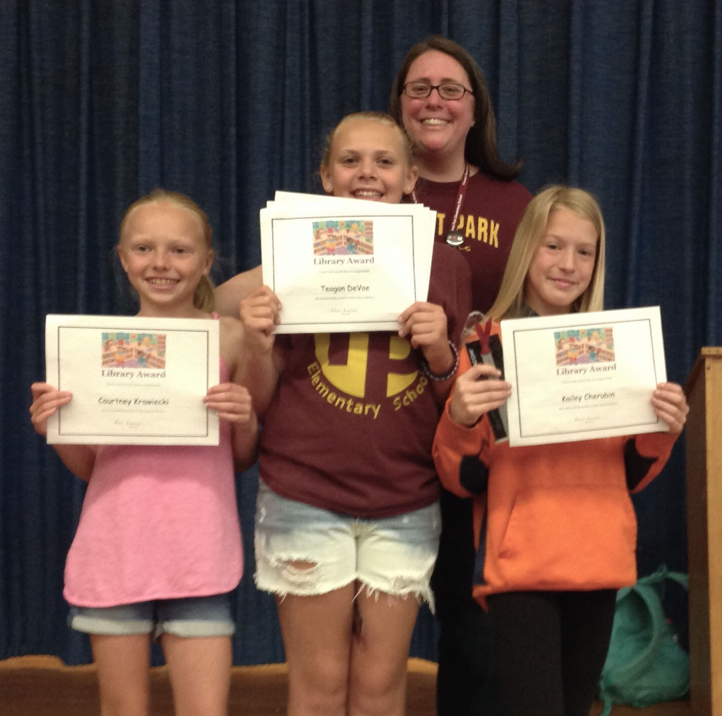 students hold their award certificates on stage