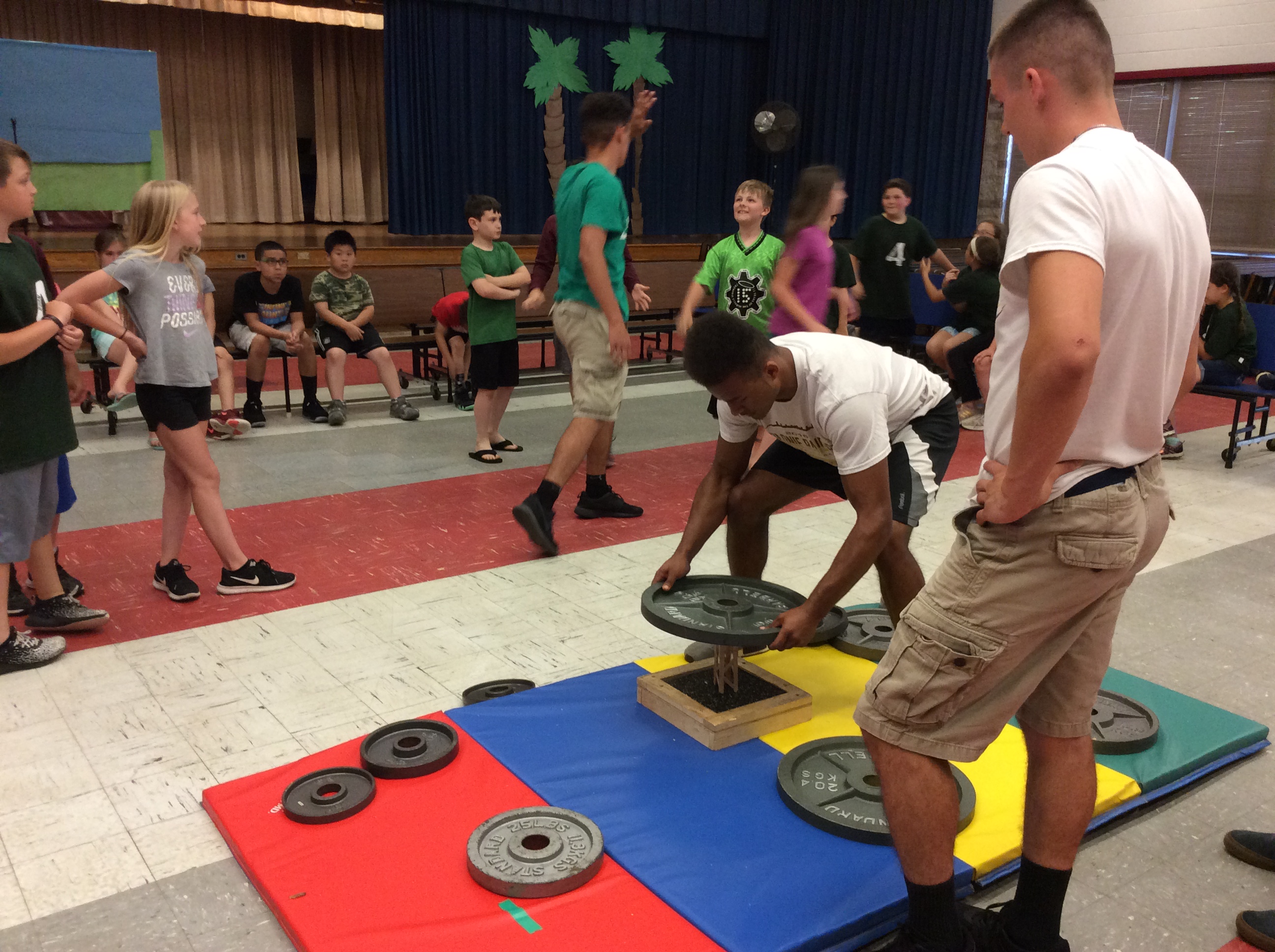 football players help lift weights onto technology challenge devices