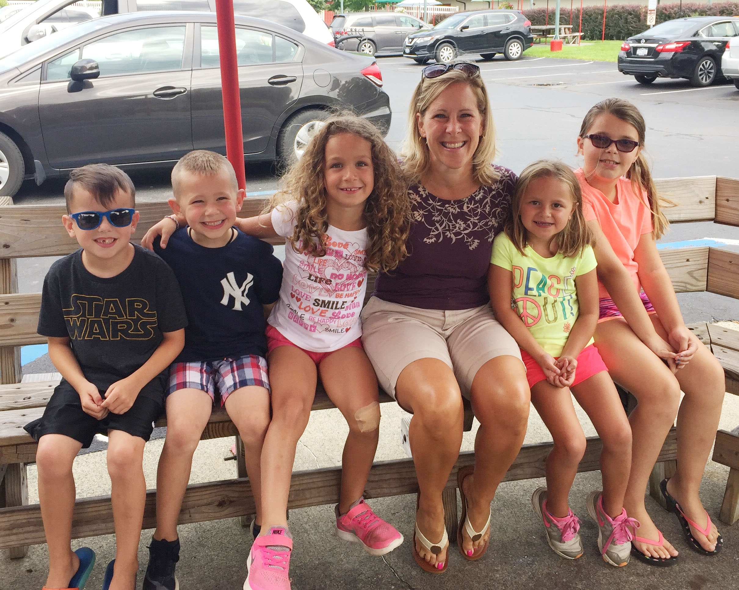 teacher sits on a bench with 5 young students