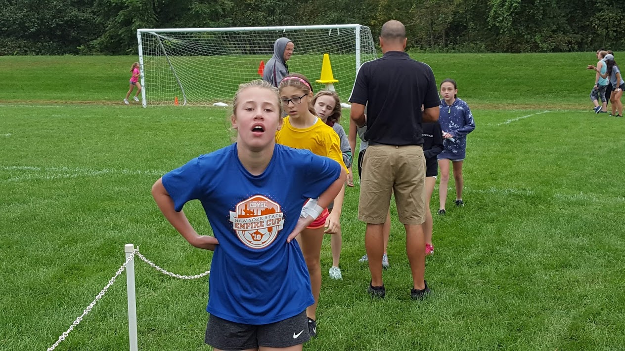 girl crosses finish line hands on hips exhausted from running