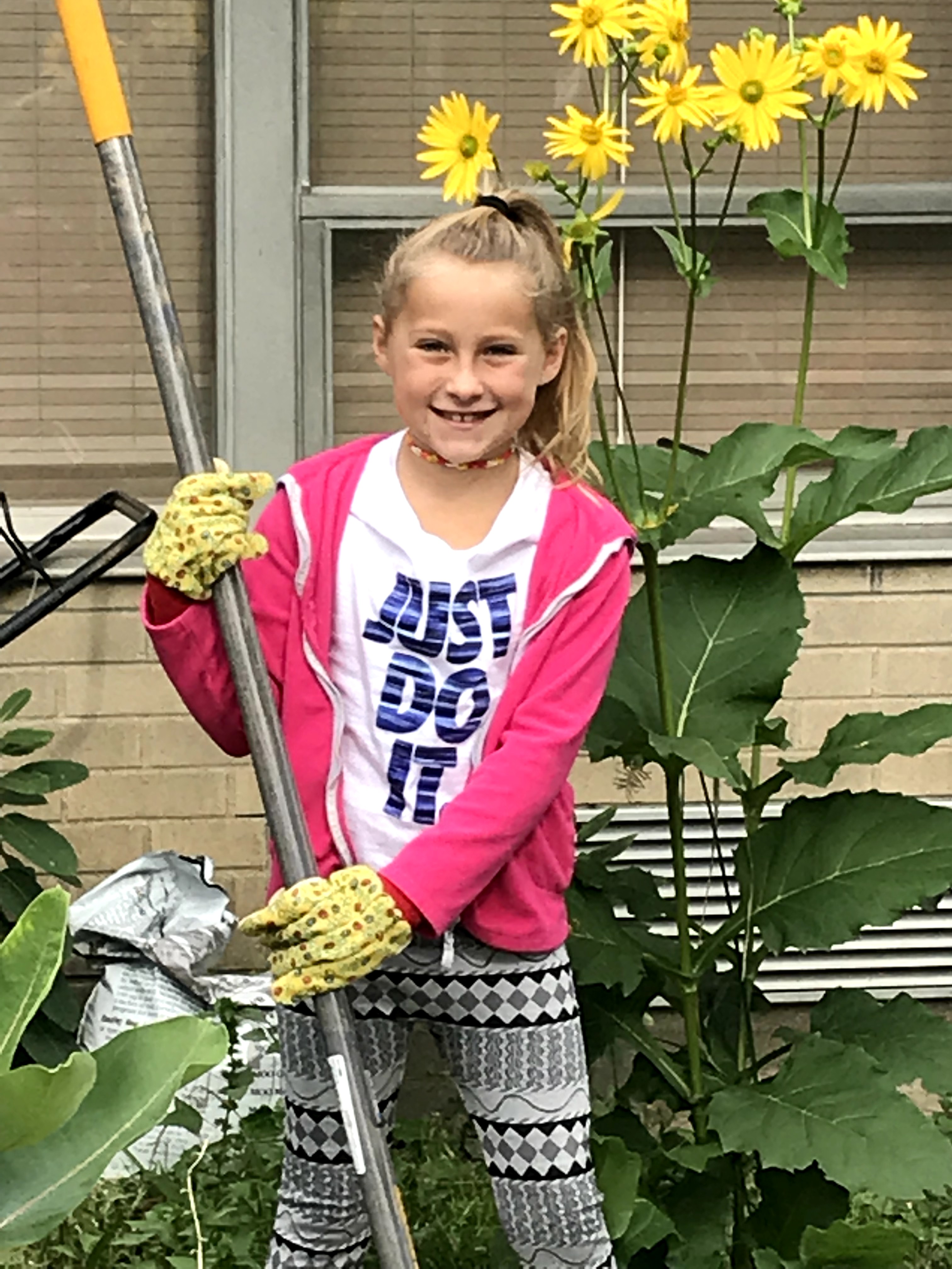 pony tail girl holding a rake and smiling