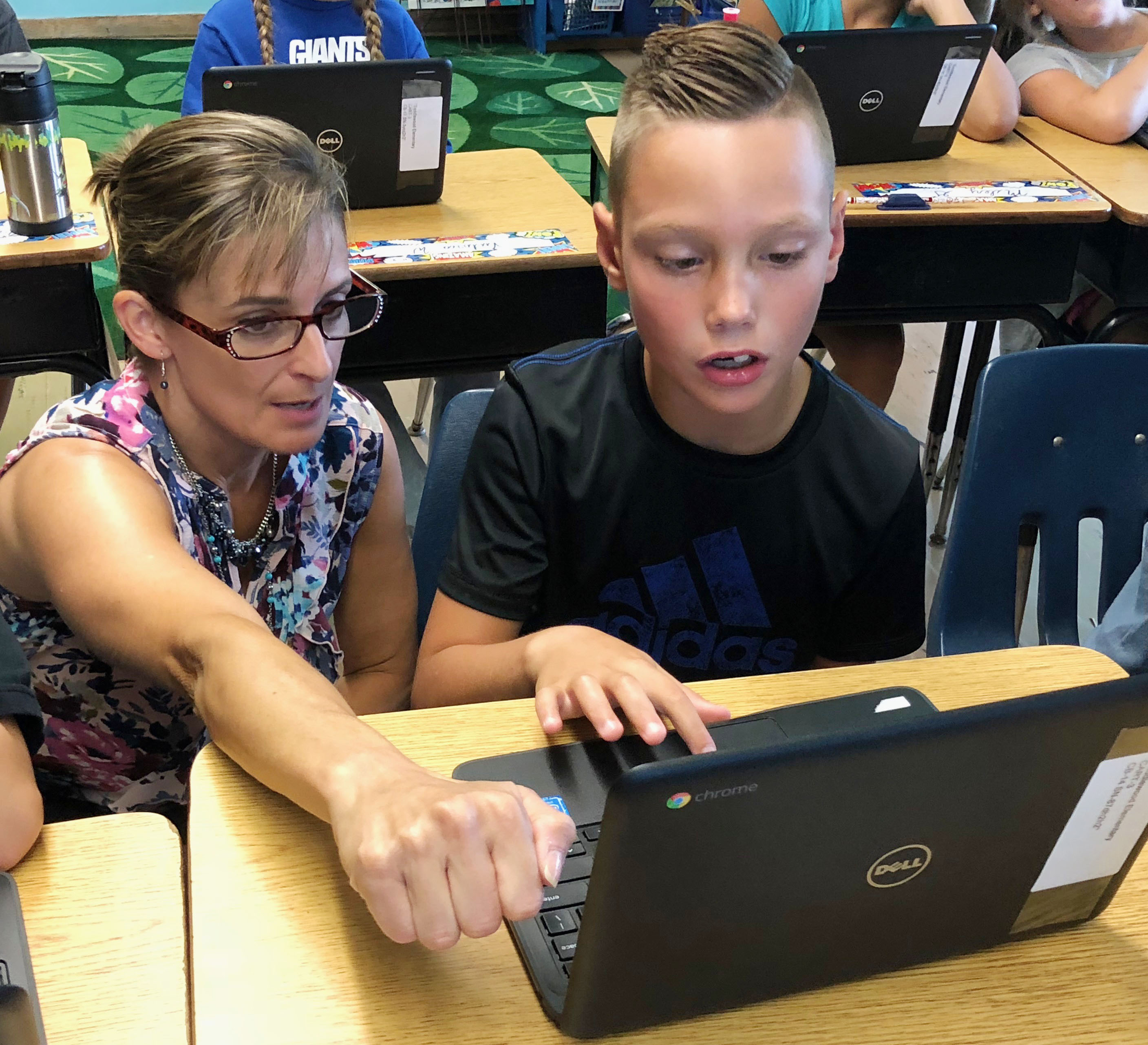 teacher helps boy at a laptop