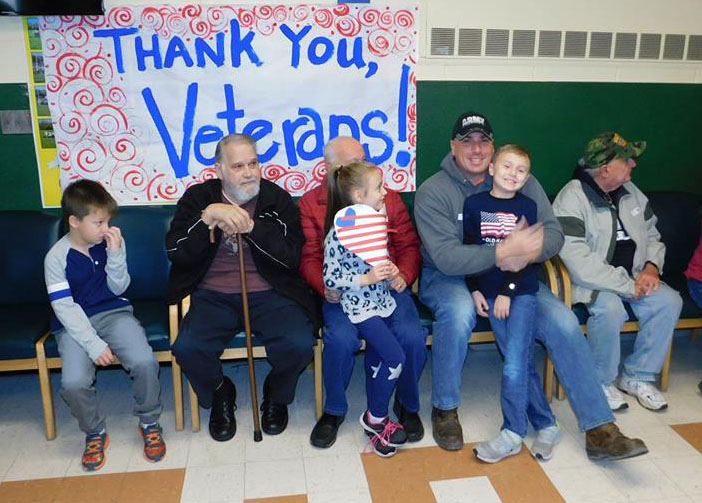 veterans sit on a bench with young students