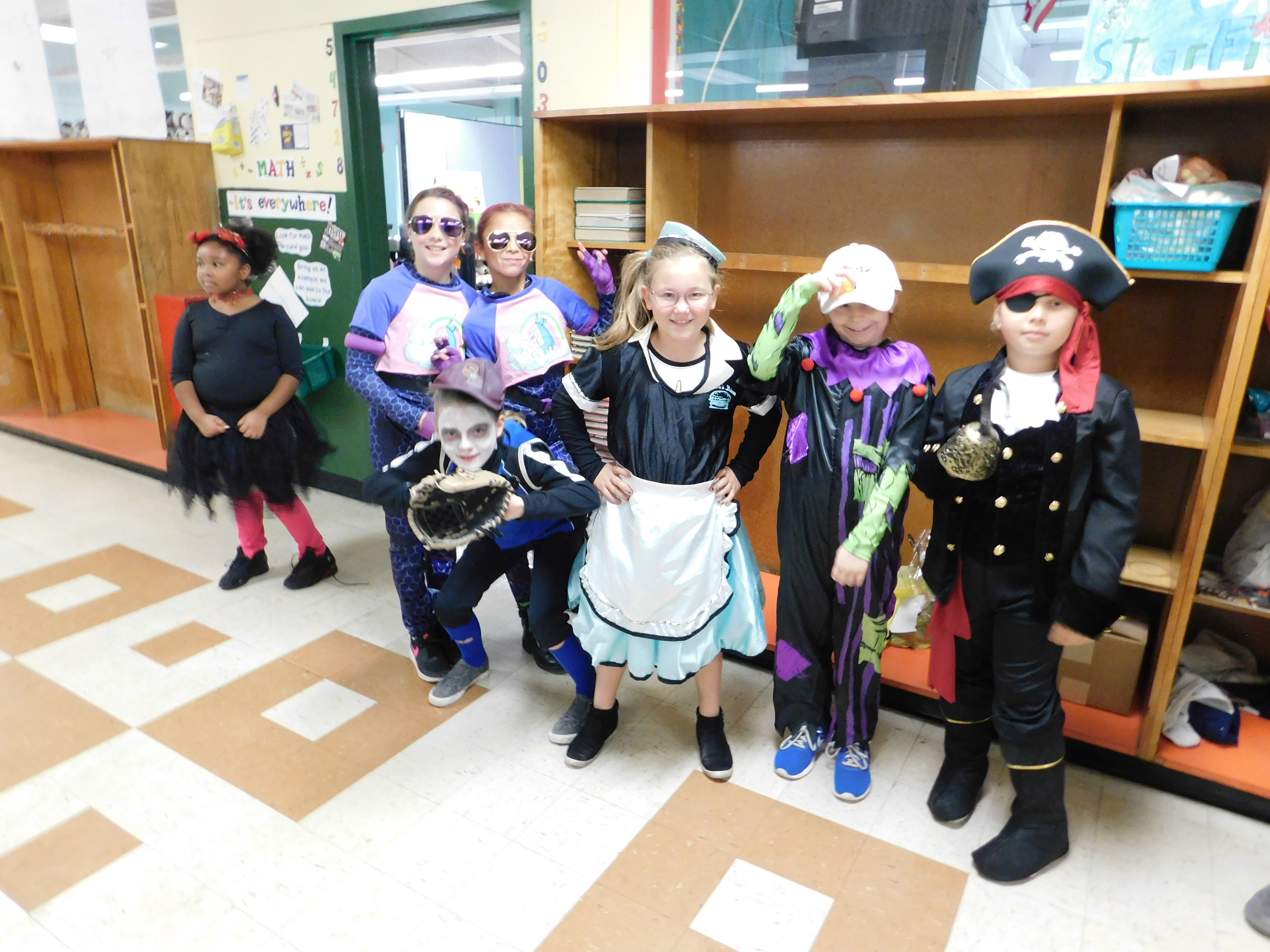 children stand in the school hall wearing their halloween costumes