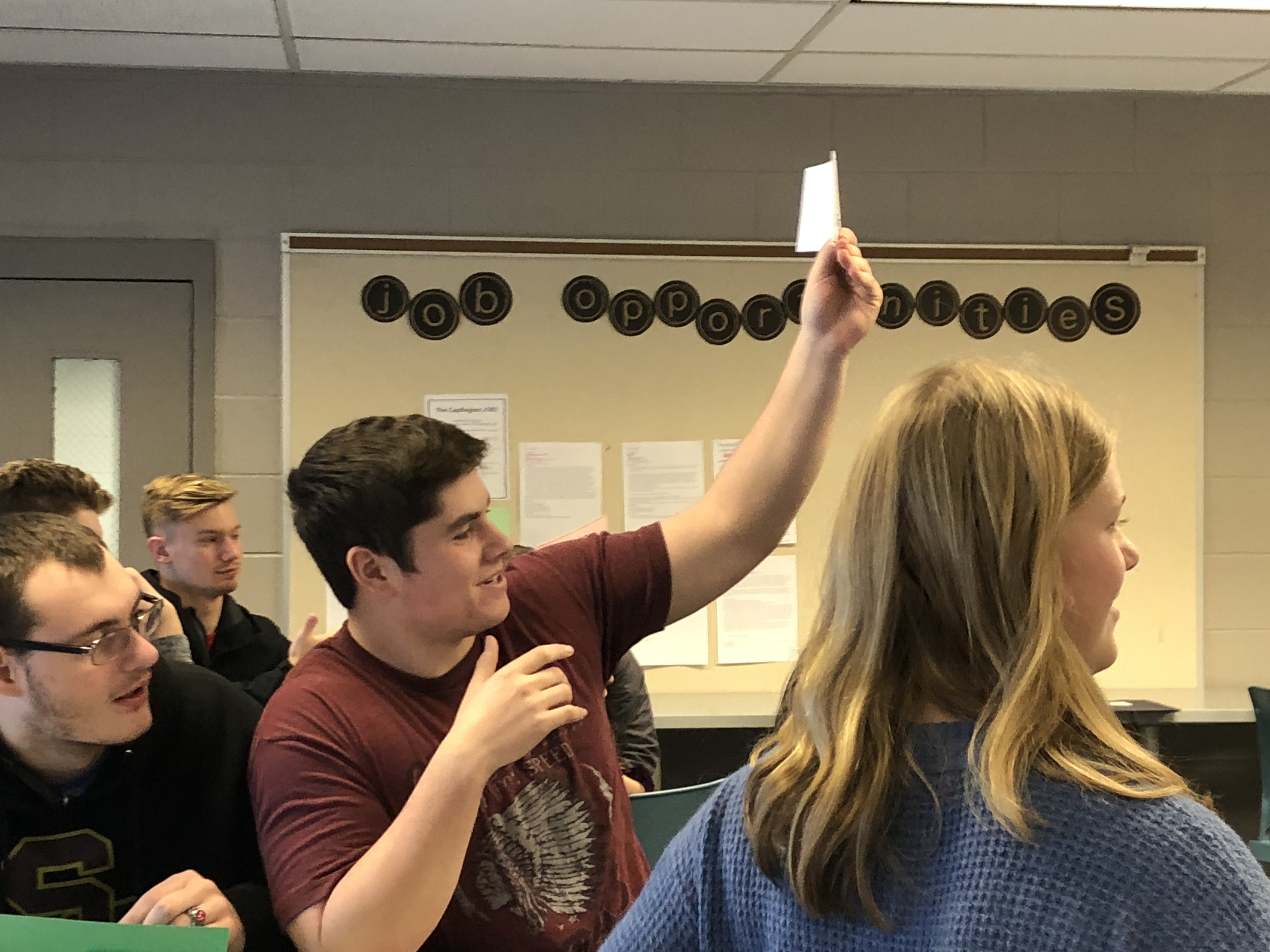 student holds up a card at a desk