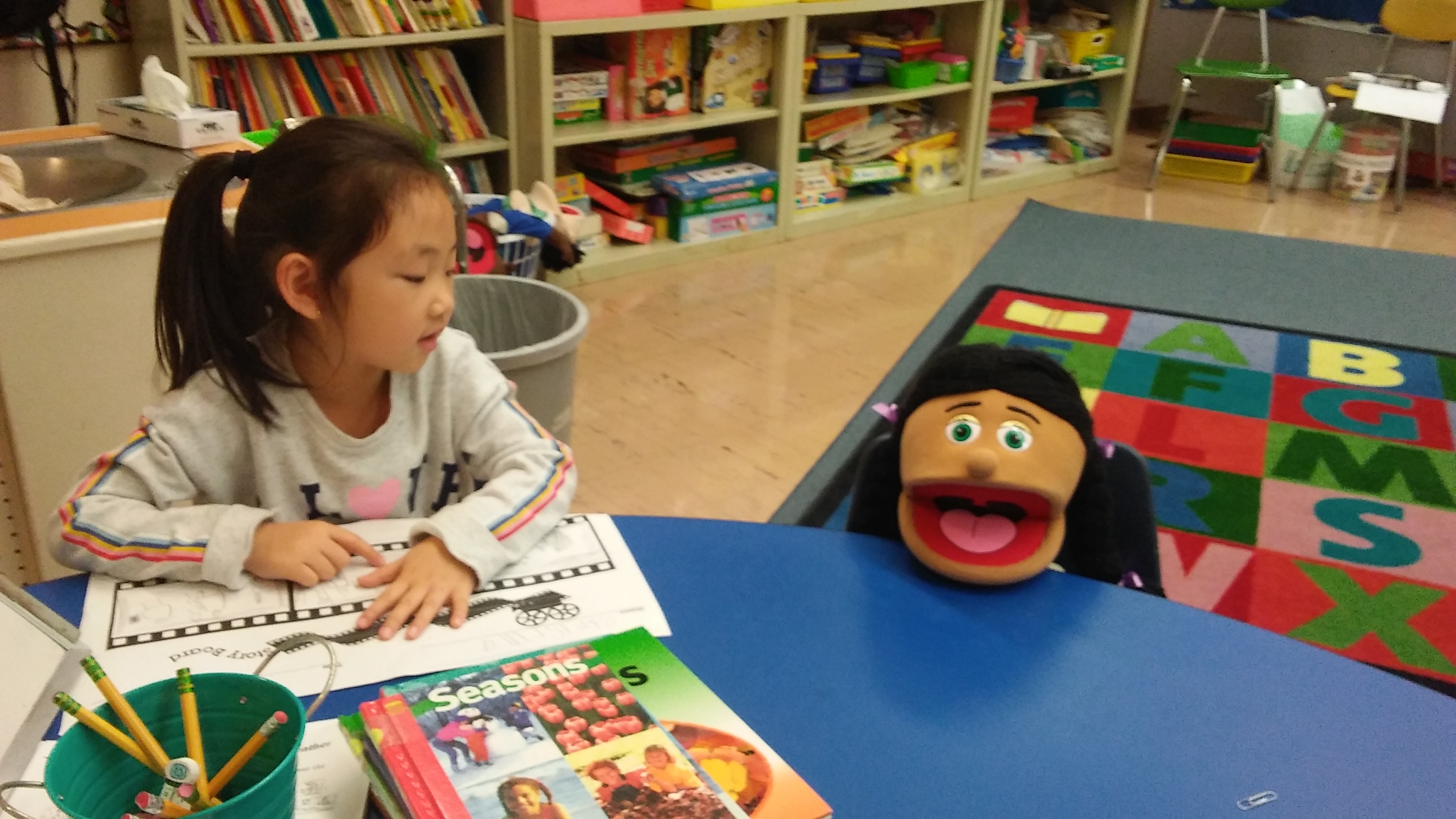 asian girl at a table with a puppet