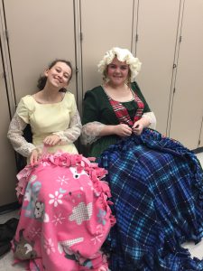 two girls in Christmas costumes with blankets on their laps