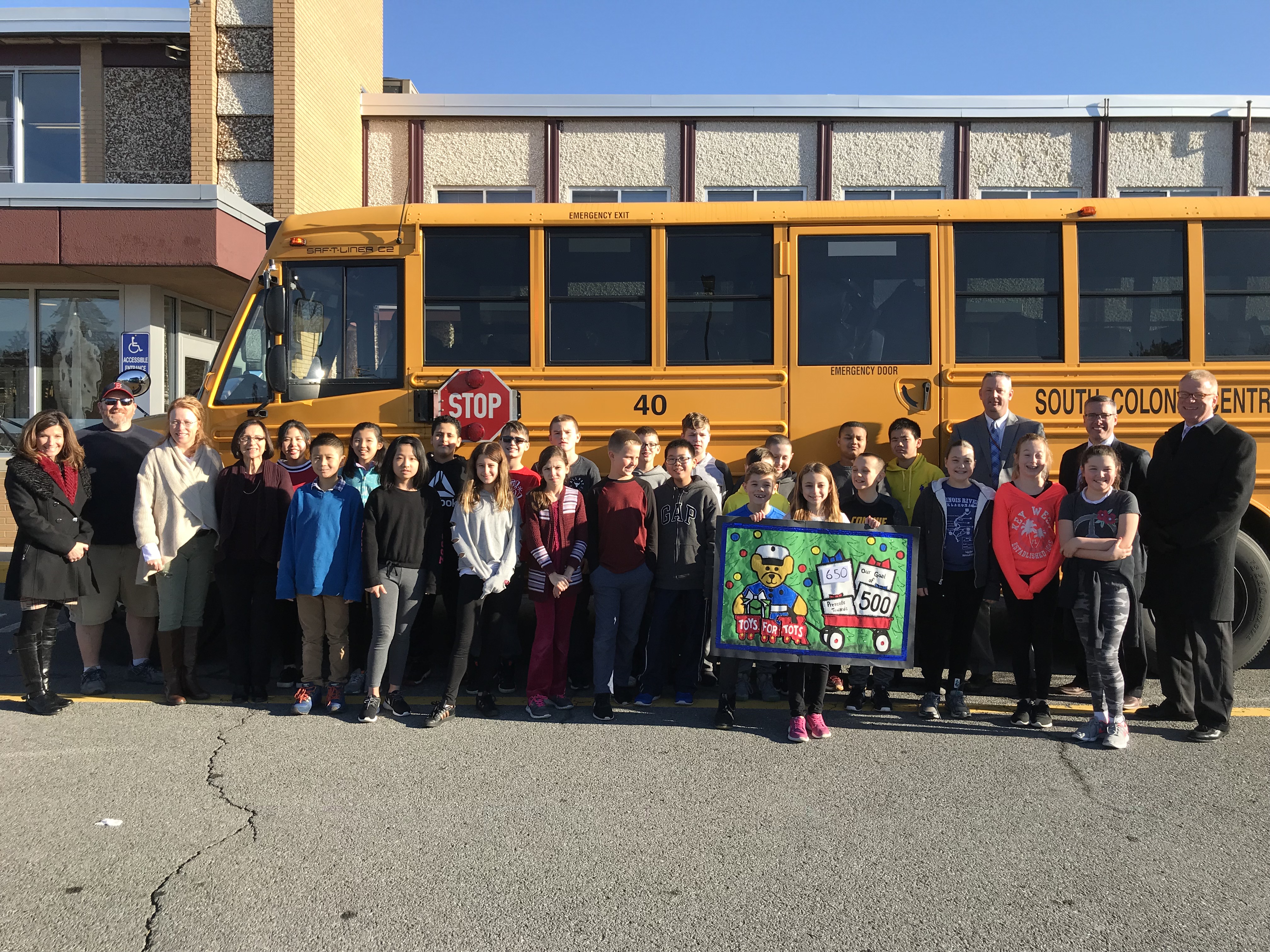 children staff outside a school bus with their toy collection