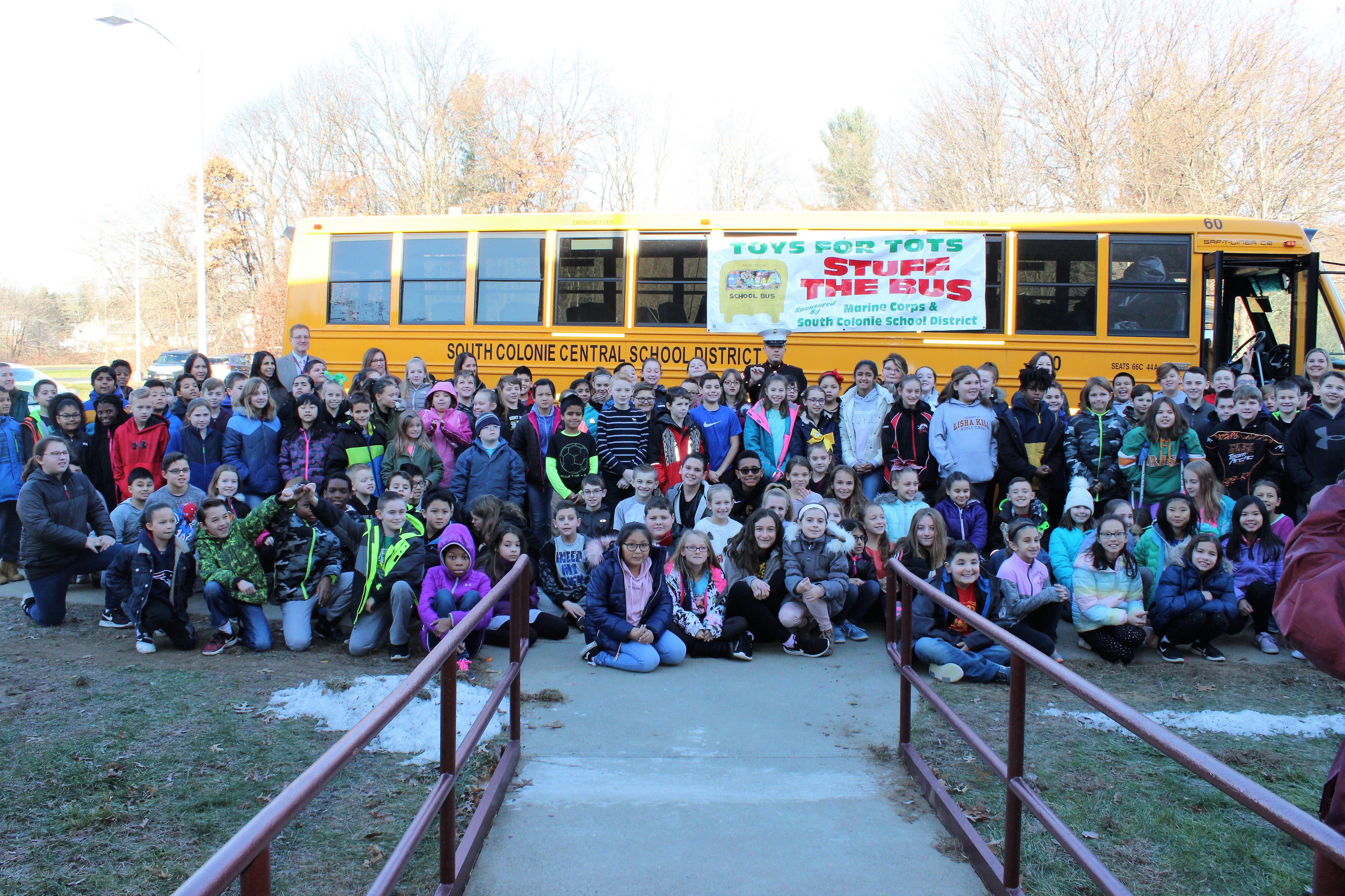 students stand outside the school bus