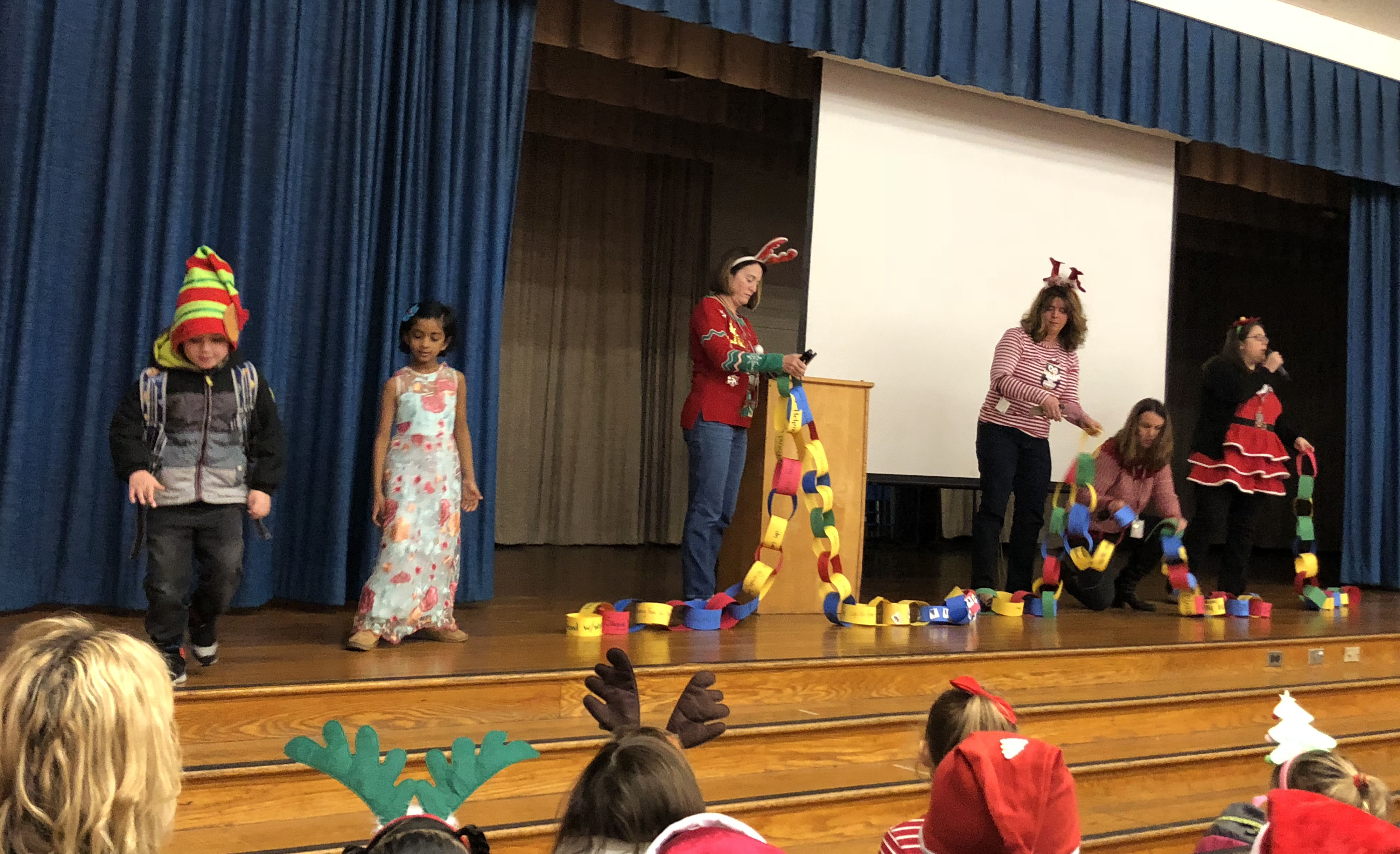 teachers on stage assemble a chain made of rolled paper link