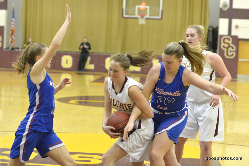 girl wrestles for the basketball among defenders