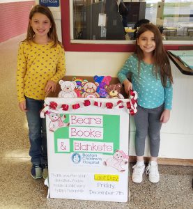 two girls stand near a collection box