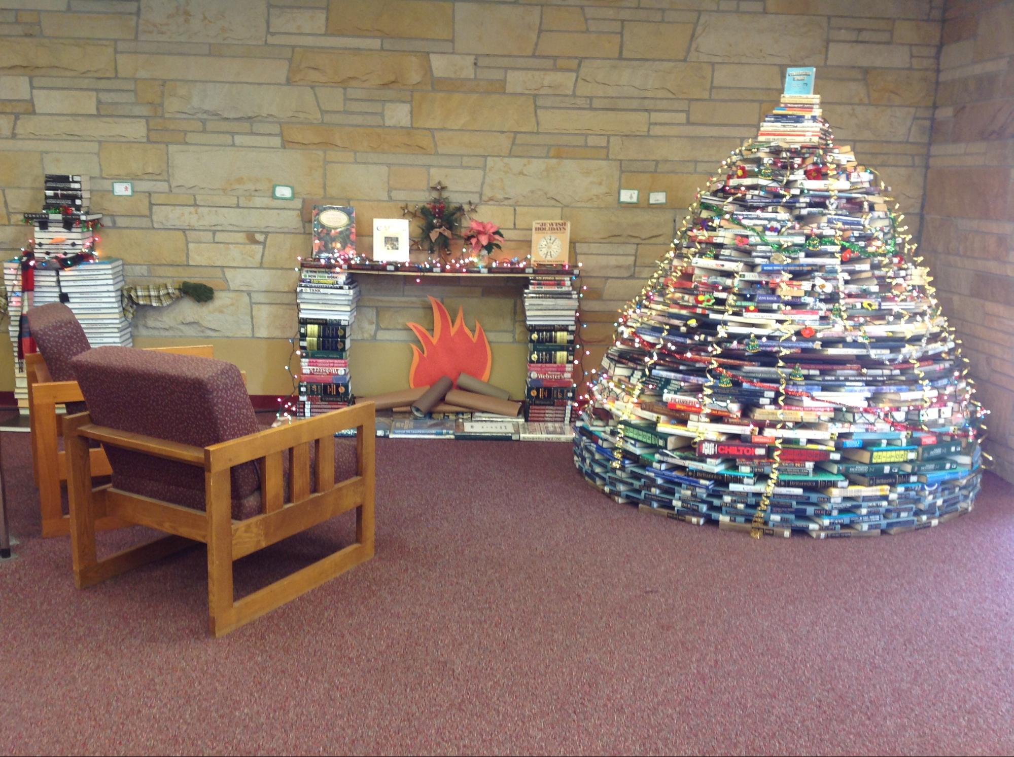 a Christmas tree made out of book near a fireplace