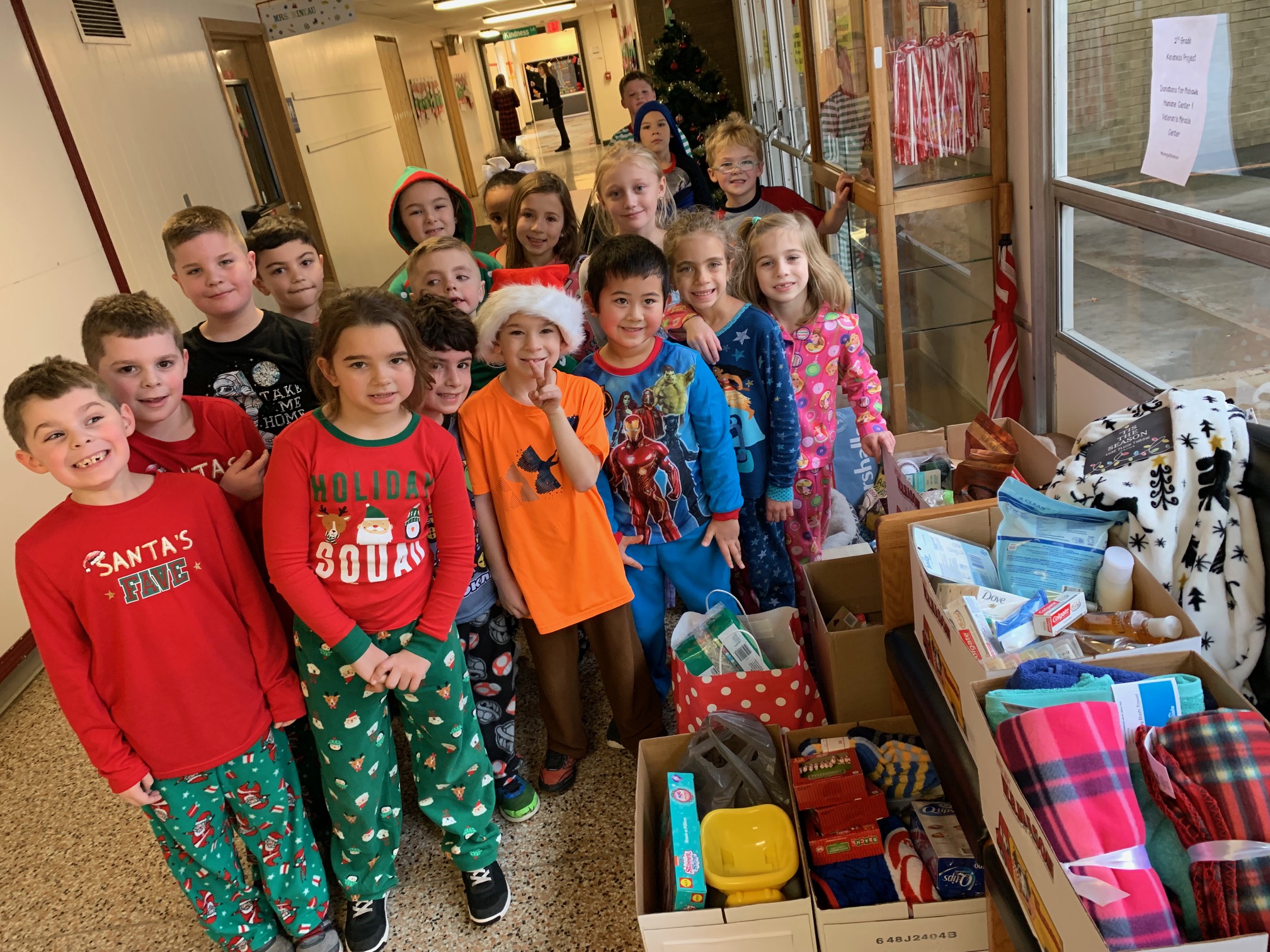 second graders stand in front of stacks of donations