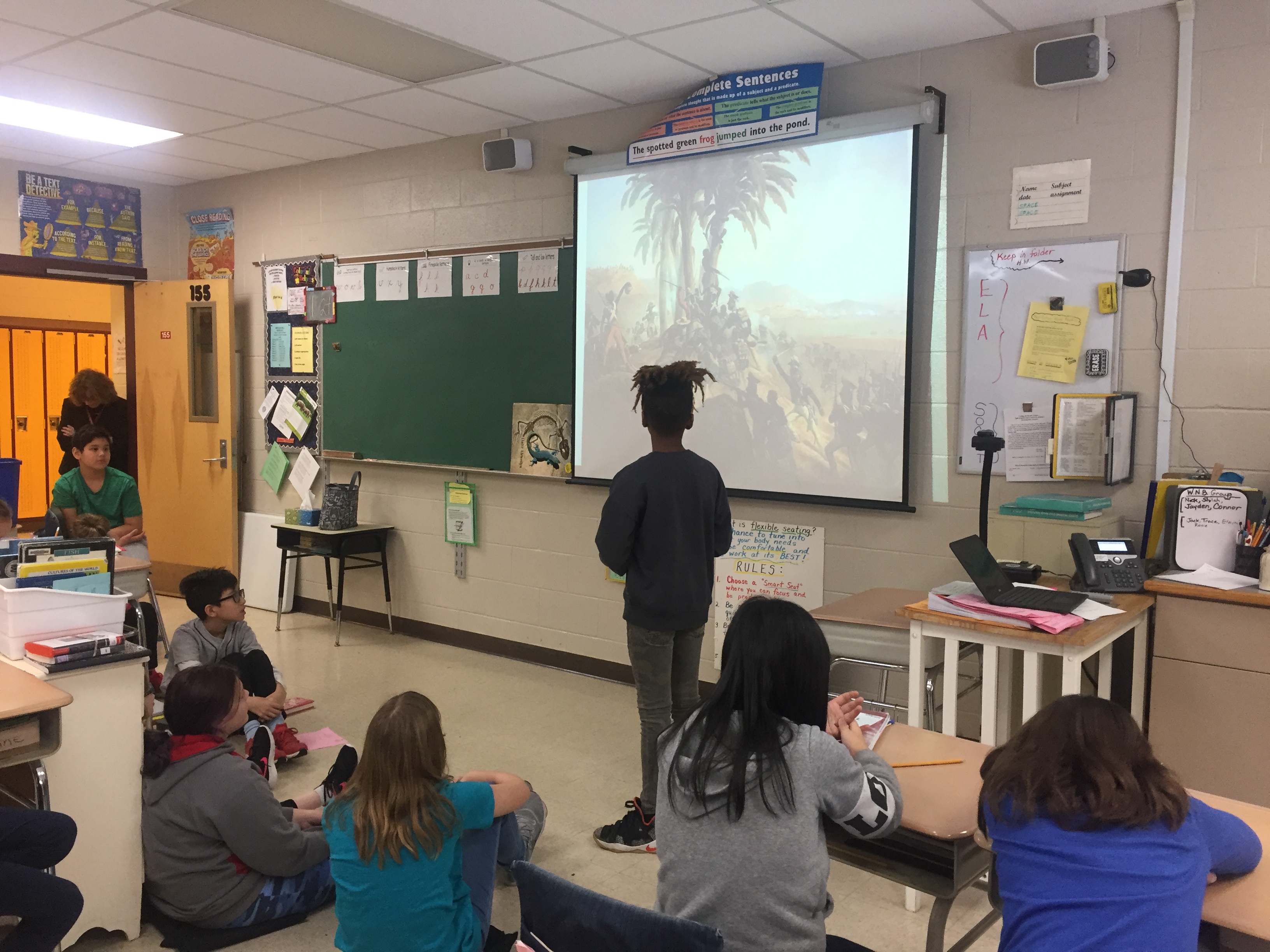 student stands in front of class