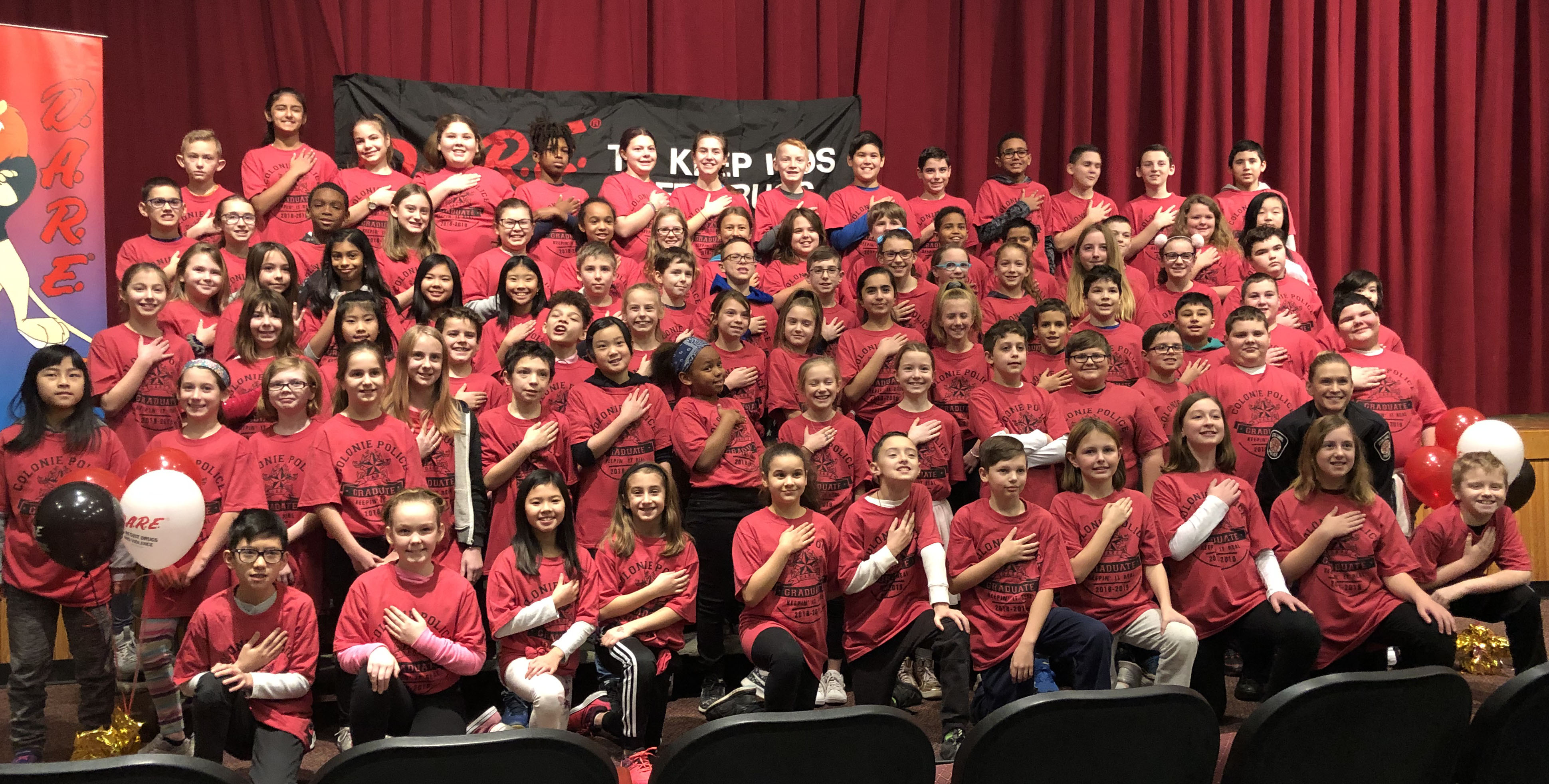 large group of students pose in their red shirts with DARE certificates