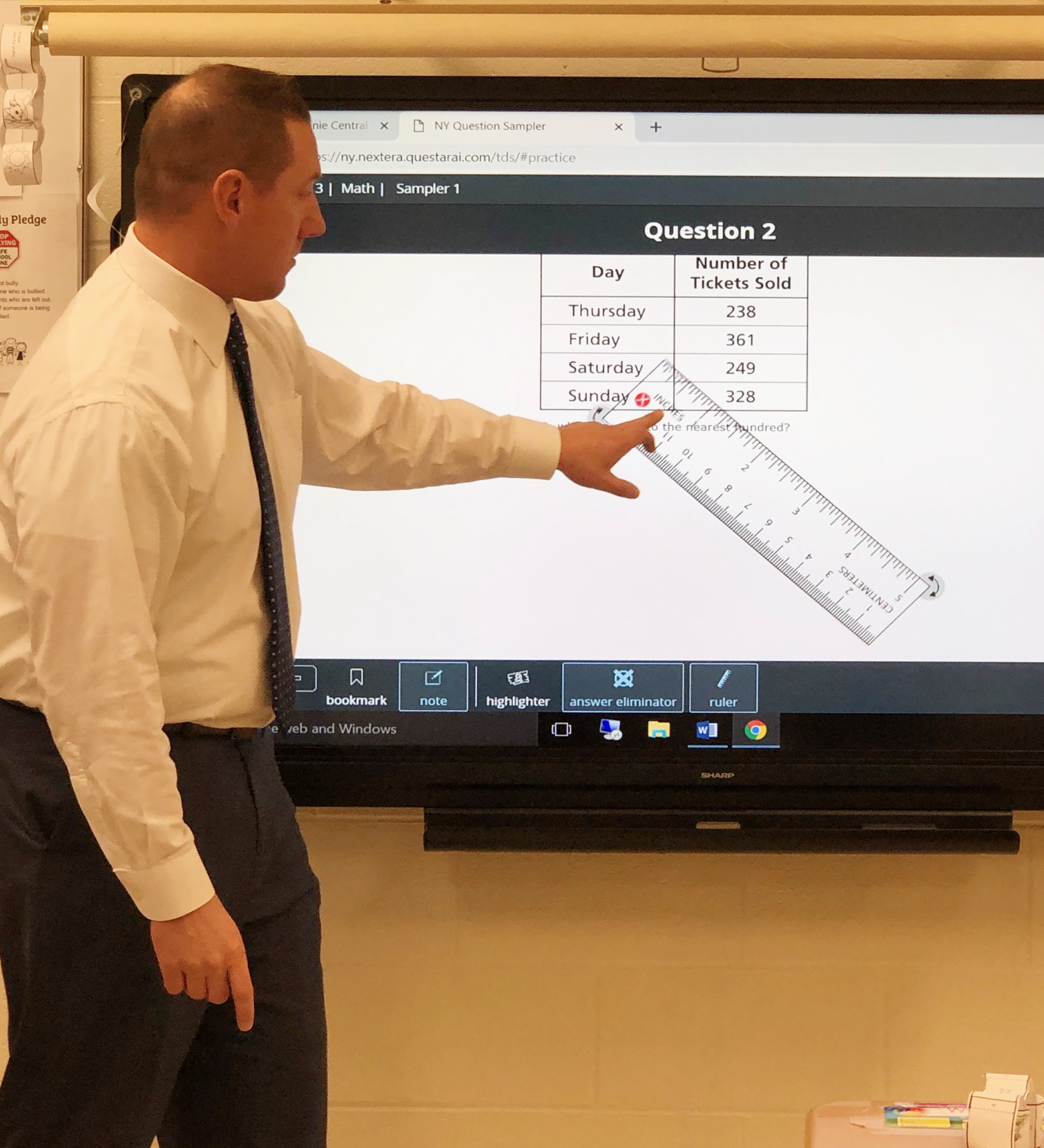 teacher in front of class pointing to visual board