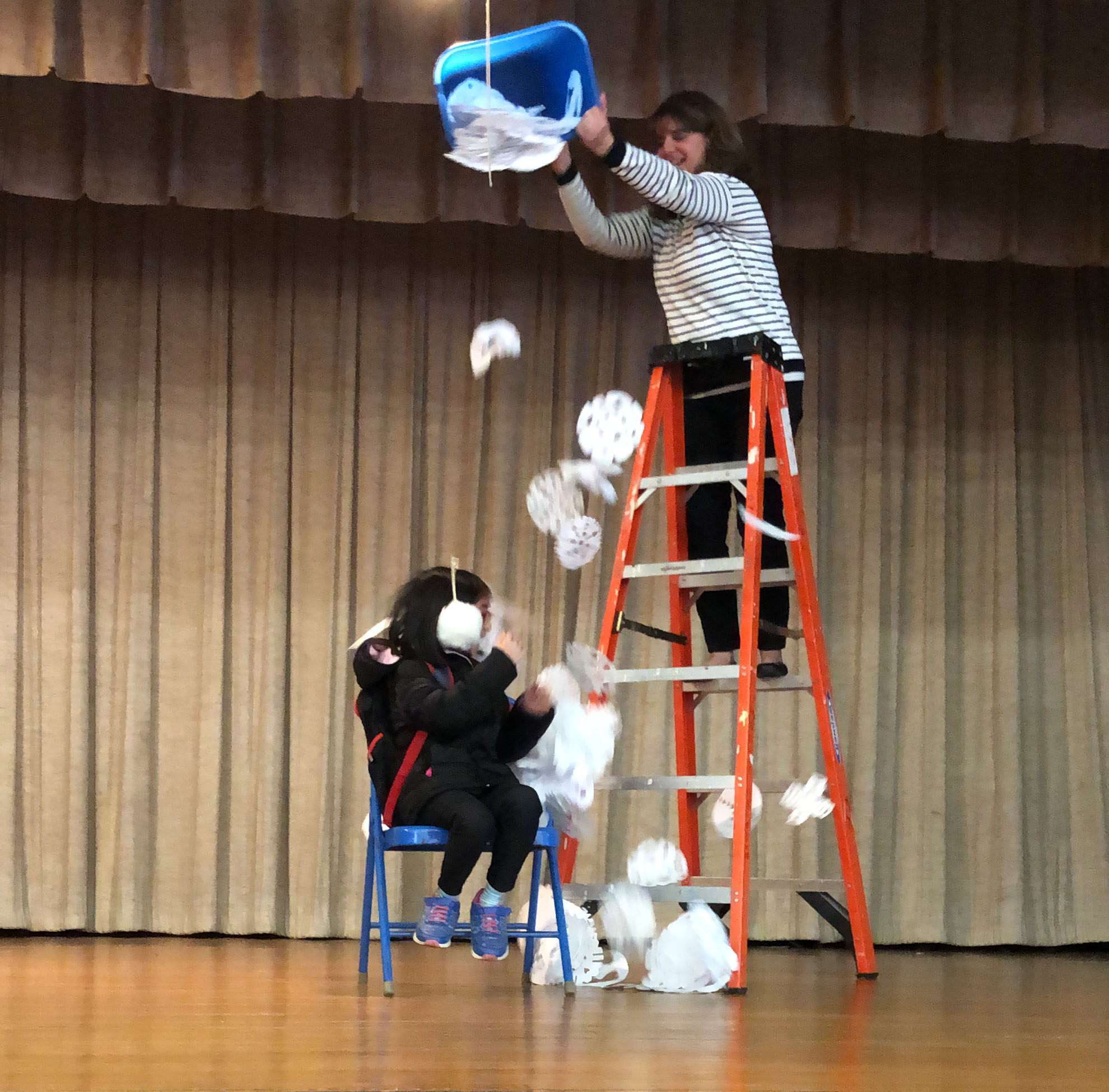 teacher on ladder pour paper snowflakes on a student from a bucket