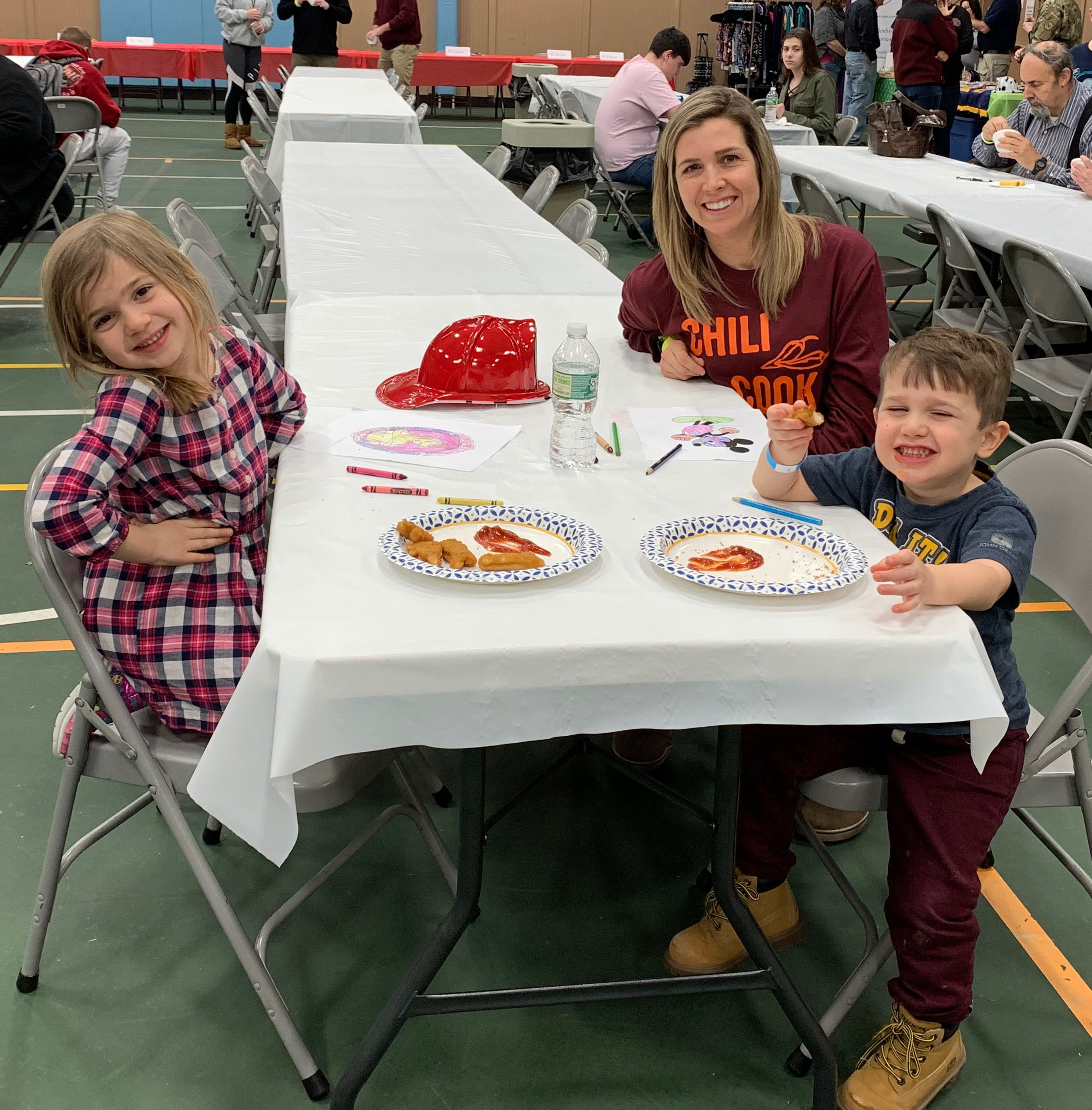 move and two children sit at table sampling chili