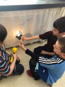 young students shine a flashlight on a wall